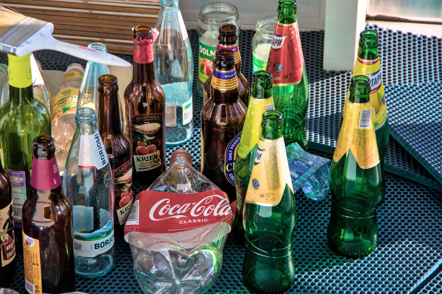 Стеклянные и пластиковые помытые бутылки стоят на балконе